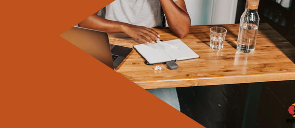 Image of a person seated at a table, looking at a laptop